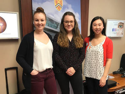 Megan Ferguson Van Alstine, Rachel Exler and Rachel Ng stand in front of the WOVS banner.
