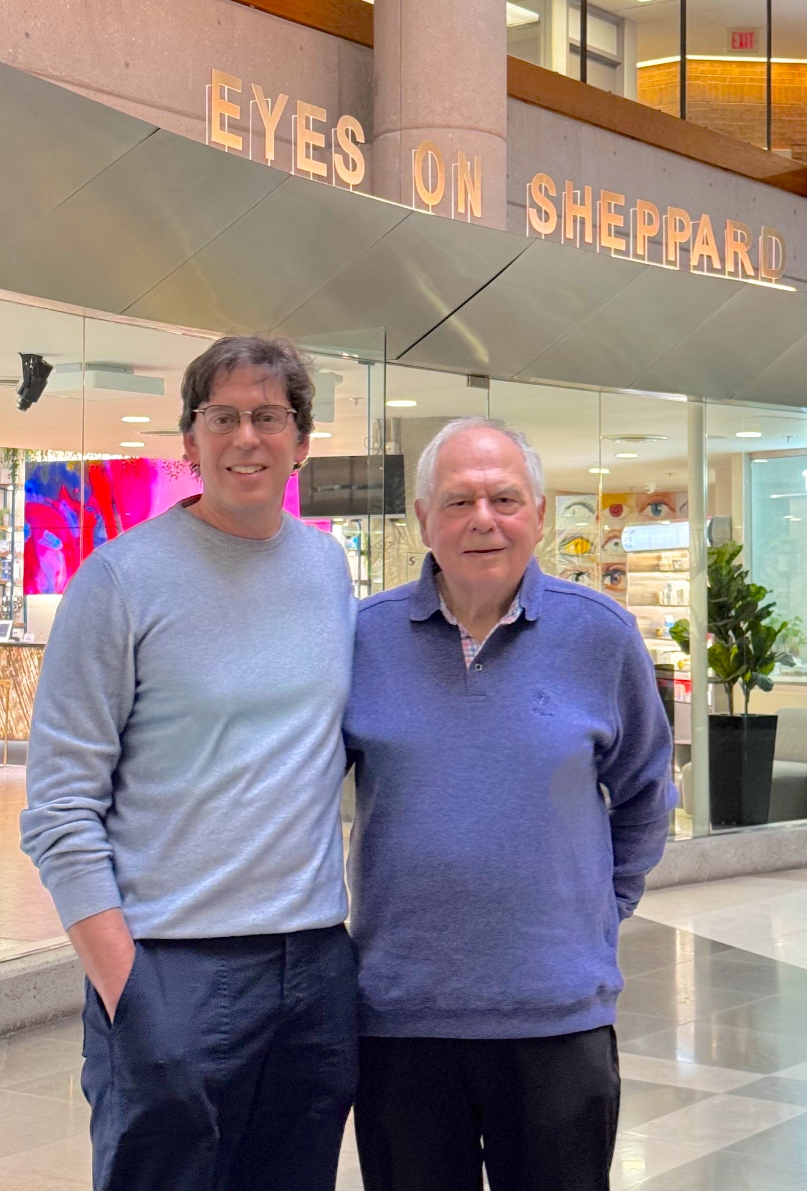 Drs. Stan and Kerry Salsberg stand in front of an Eyes on Sheppard sign.