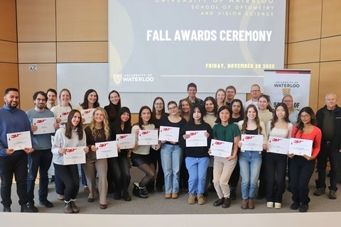 Students holding their awards and smiling along with faculty and donors.