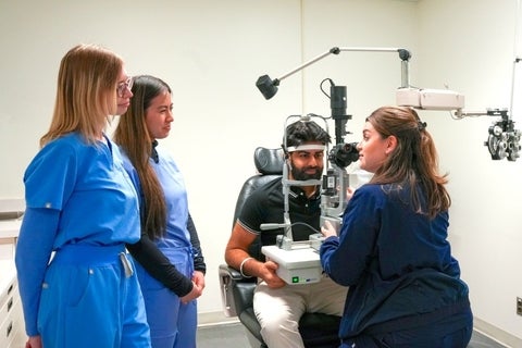 Two students watch as professor performs slit lamp exam