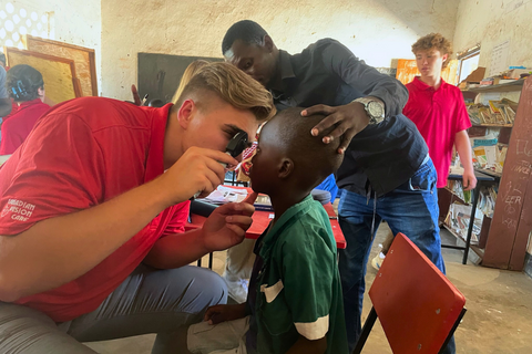 Elijah Bouma holding a direct ophthalmoscope to a child's eye.