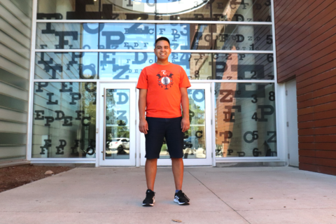 Man wearing an orange "every child matters" t-shirt standing in front of the Optometry building entrance.