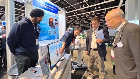 Researchers from CEVR, on SLOPE team, explaining their invention to two men in suits.