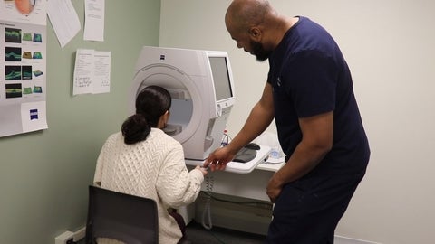 Optometrist with patient at machine