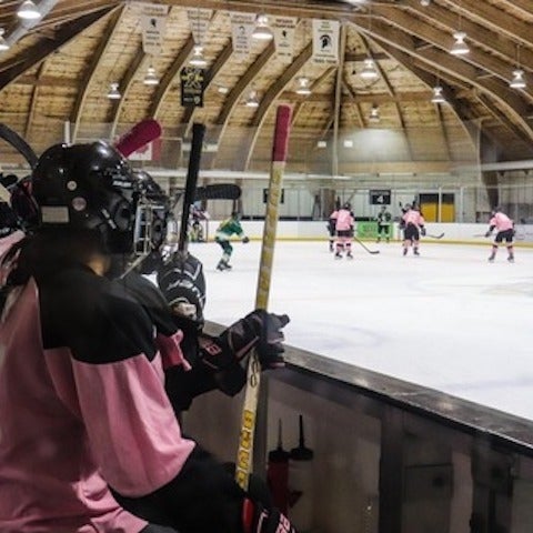 hockey players on pink team's bench watching game on ice