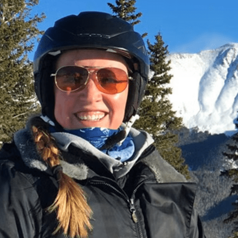 Kristine Dalton stands in front of a snow-covered mountain vista.