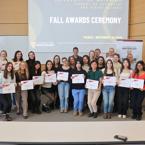 Students holding their awards and smiling along with faculty and donors.