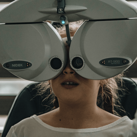 young girl looking through optometry device