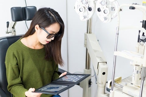Woman wearing sunglasses looking at a tablet in an optometry exam room