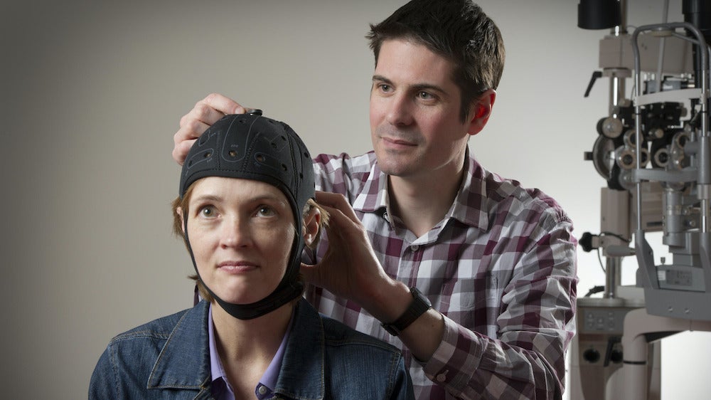 Ben Thompson adjusting a testing apparatus on a female patient's head.
