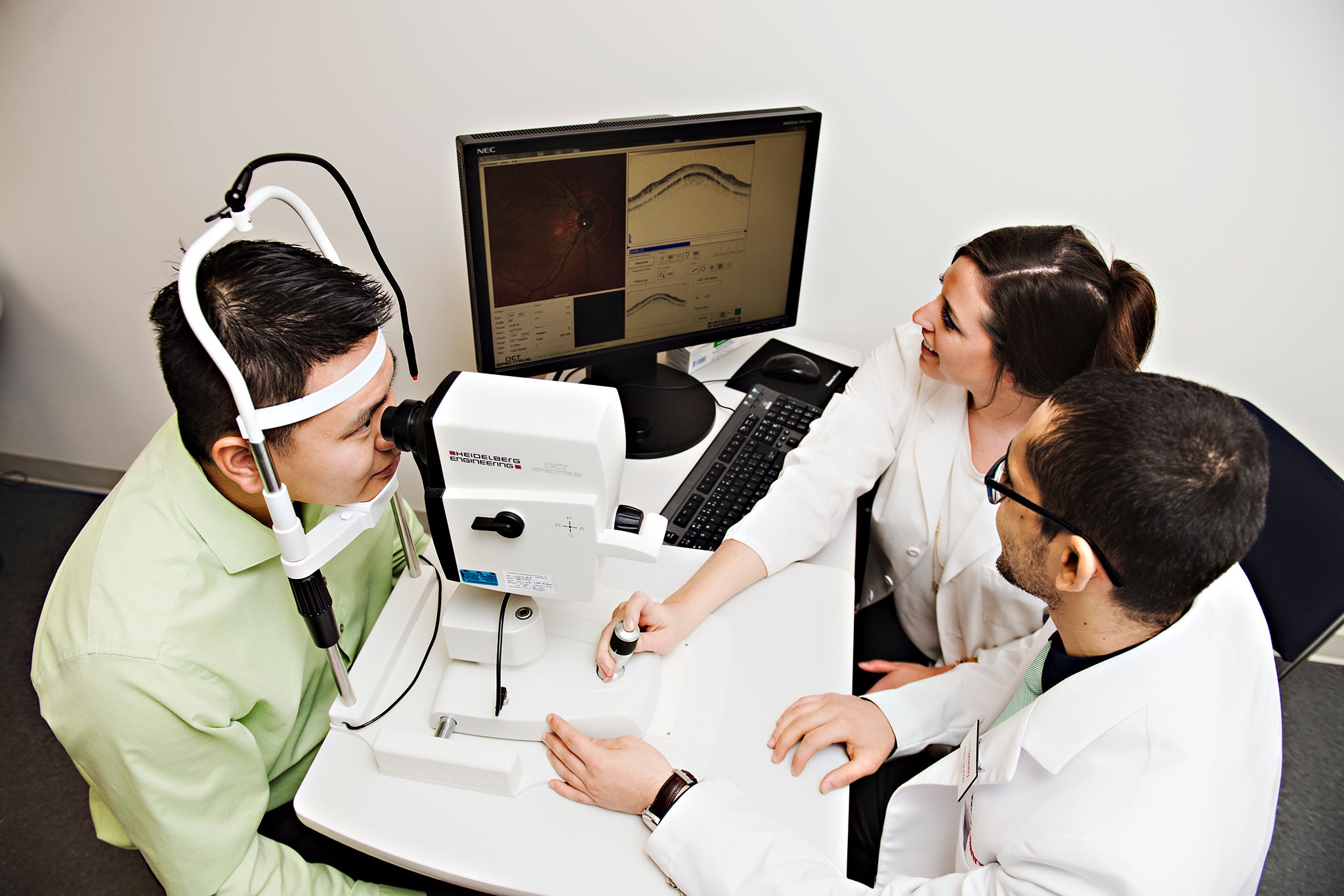 Two researchers and a patient using vision science equipment for testing