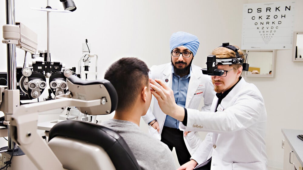 Two male optometry students examine a patient.