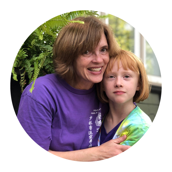 Woman in a purple shirt cuddles a little red-haired girl