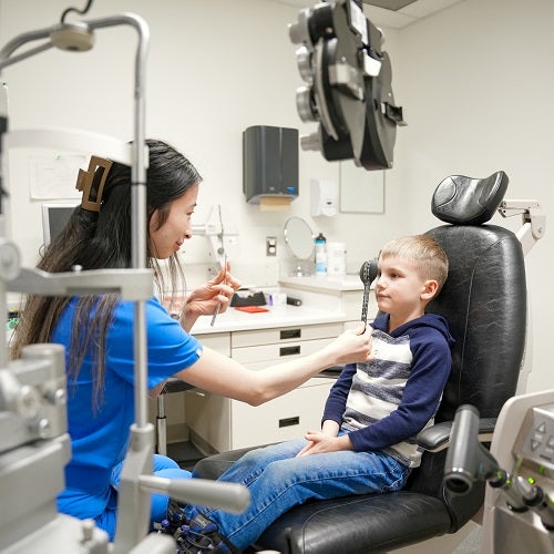 An optometry student gives an eye exam to a young patient