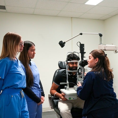 Students look on as a professor demonstrates eye exam techniques