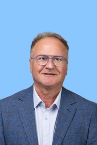 headshot of man in blue suit with blue background