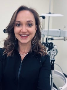 woman in black shirt smiling with optometry clinic background