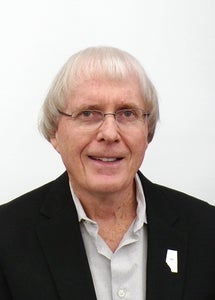 headshot of man in black suit smiling