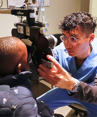 An optometrist examines a newcomer child.