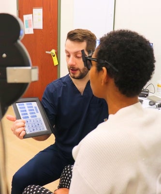 An optometrist tests a patient's vision using symbols on an iPad.