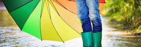 green boots with umbrella standing in a puddle of water