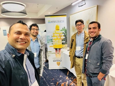 Four men standing in front of P4A banner at a conference