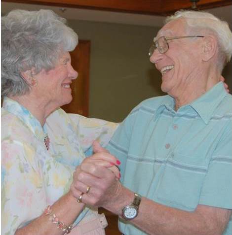 An older couple dances and smiles.
