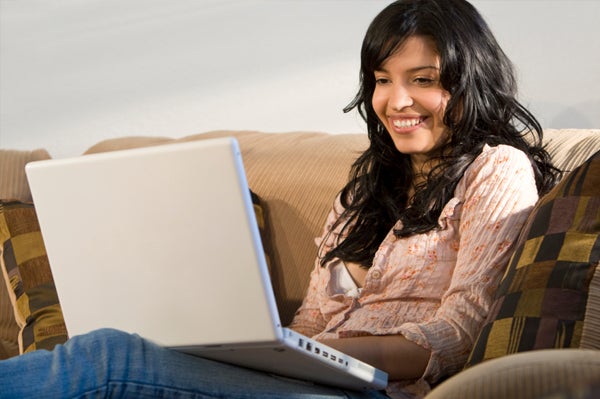 Woman smiling while looking at her laptop.