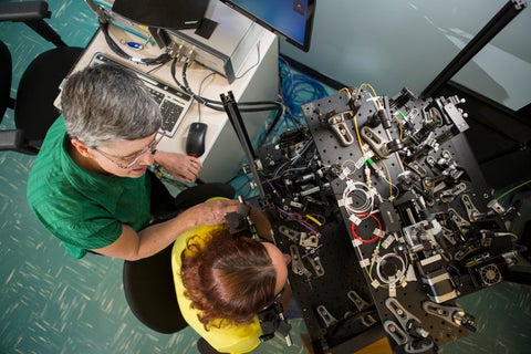Melanie Campbell using a piece of hardware to look into someone's eye.