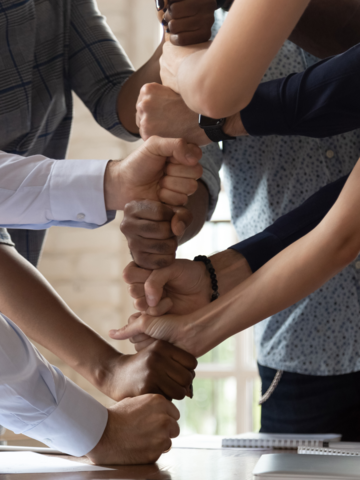 Several people with their fists stacked on top of each other