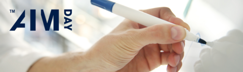 Person using a marker and writing on a whiteboard and AIMday logo