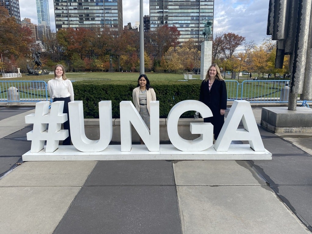 Students standing and smiling behind a #UNGA sign