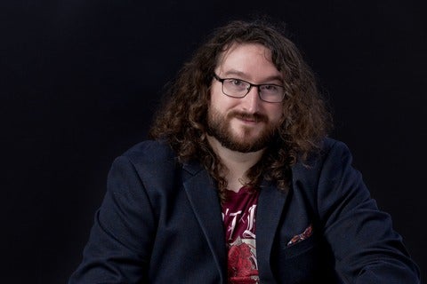 Dustin sits smiling in a jacket and shirt