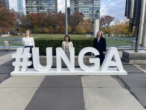 Students standing and smiling behind a #UNGA sign