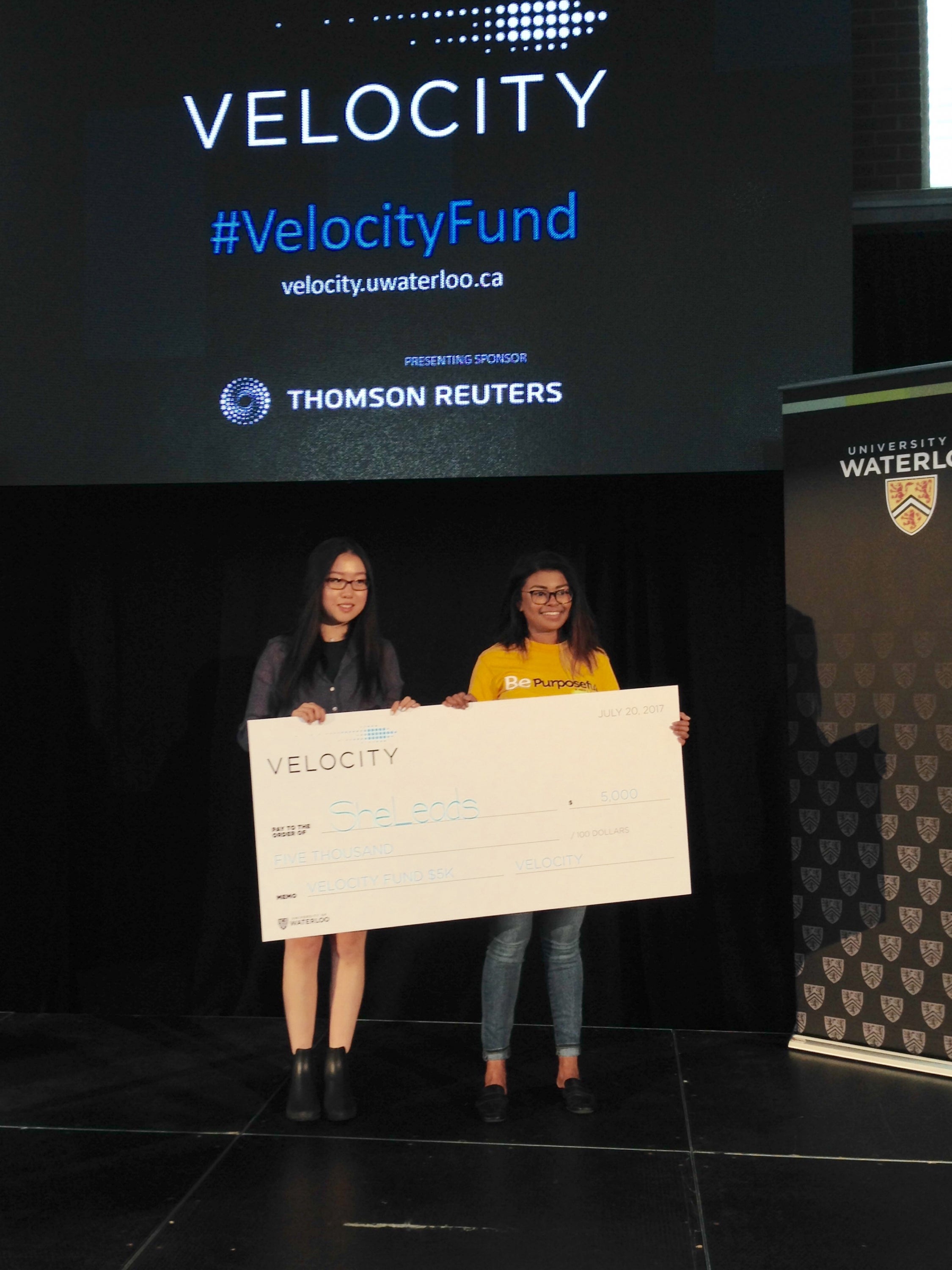 Wenqi and Cassie holding large cheque under velocity sign