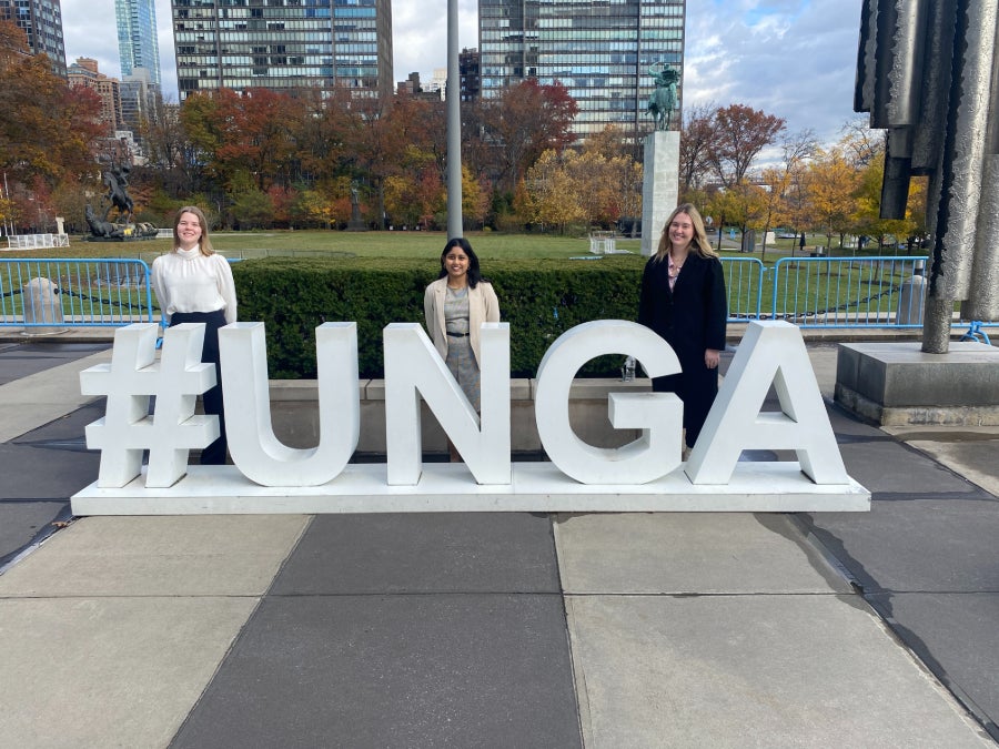 Students standing and smiling behind a #UNGA sign