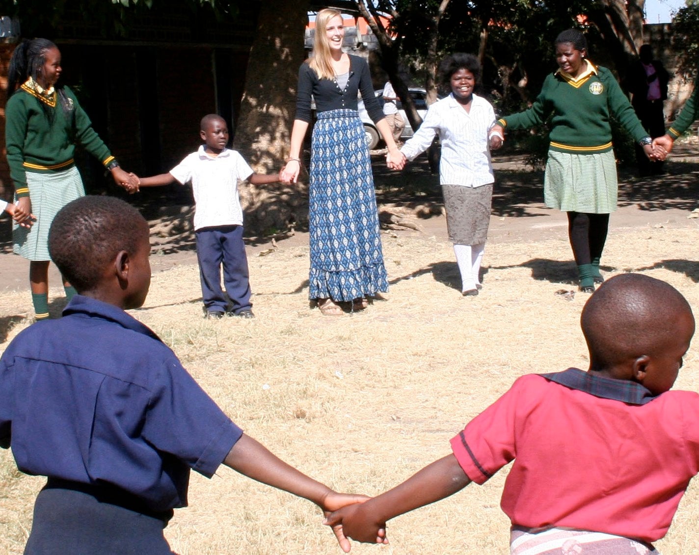 Rachel holding hands with Zambian children in a circle