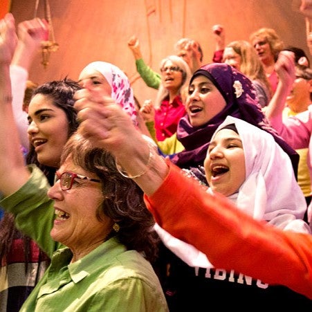 People singing joyfully wearing brightly coloured clothes