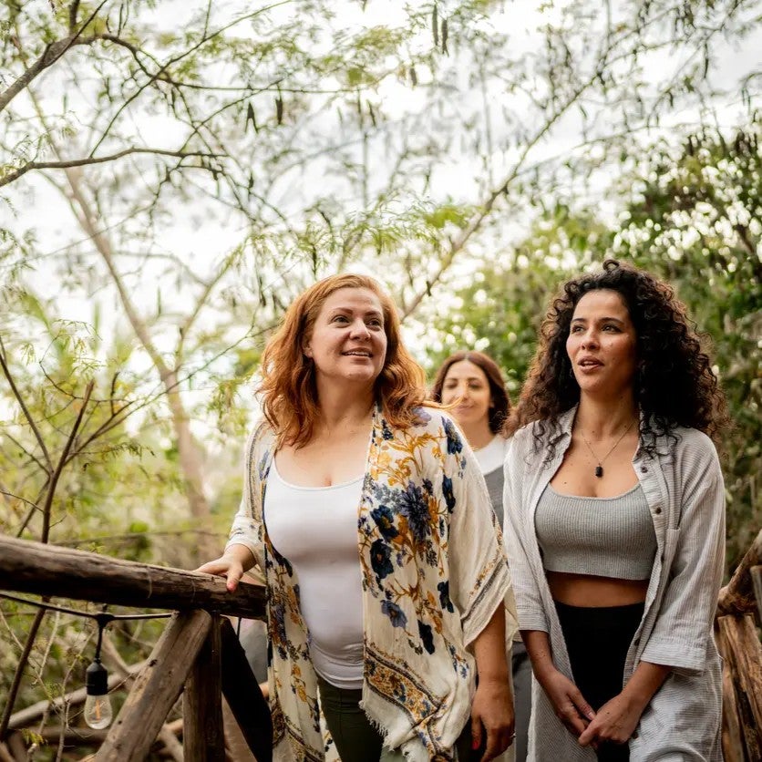 Three women crossing a bridge in a wooded area