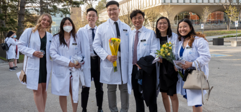 Students wearing white coats and smiling