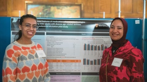 Two graduate students standing next to a poster