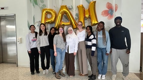 Students smiling in front of PAM balloons