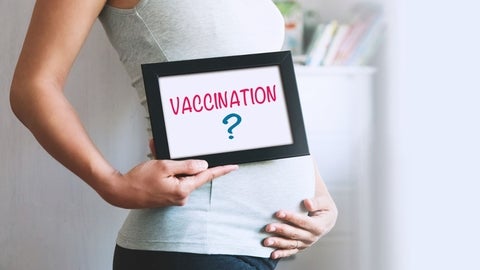 A pregnant woman holding up a sign that says Vaccination?