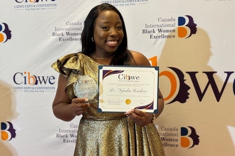 Nyasha Gondora holding up an award