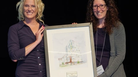 Two people holding an award plaque