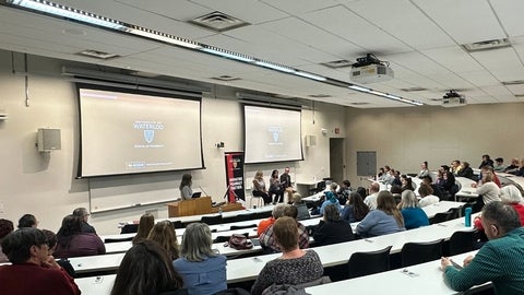 A classroom full of people listening to a presentation