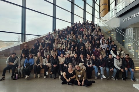 A large group of people smiling and sitting on stairs 
