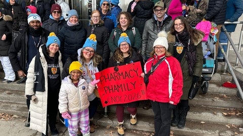 A group of people smiling and holding a sign 