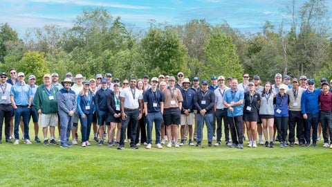A large group of people standing on the green on a golf course