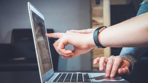 Two hands pointing at a laptop screen